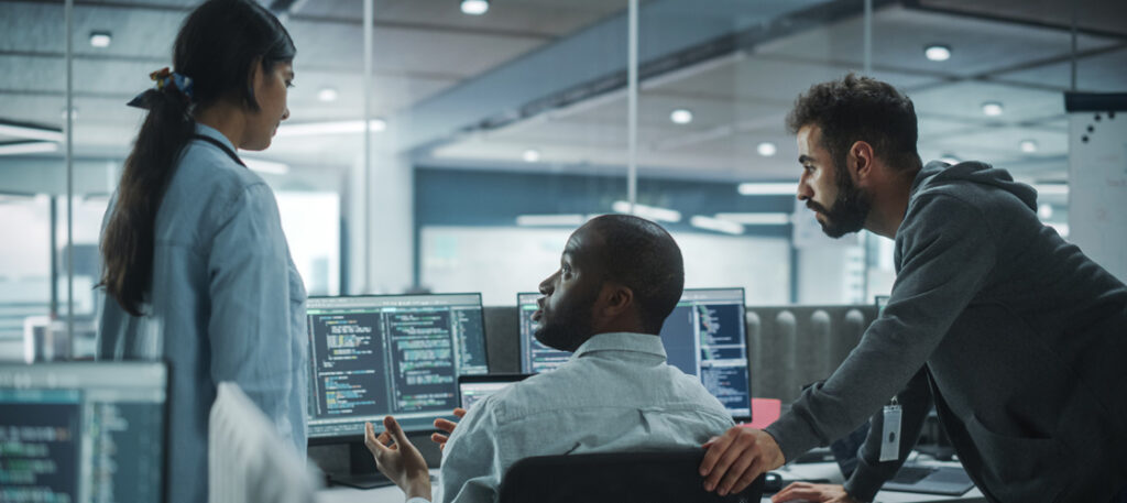 Picture of a group of cybersecurity professionals talking around a computer screen