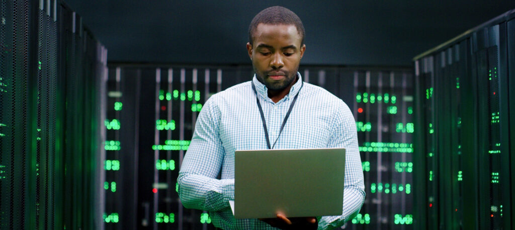 Picture of a man in a server room with a laptop